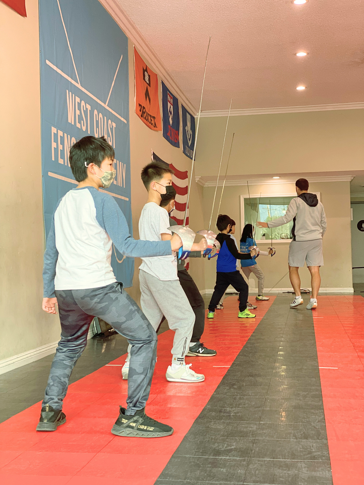 A group of pre teen kids in beginners saber fencing class at west coast fencing academy in engarde position with saber in hand