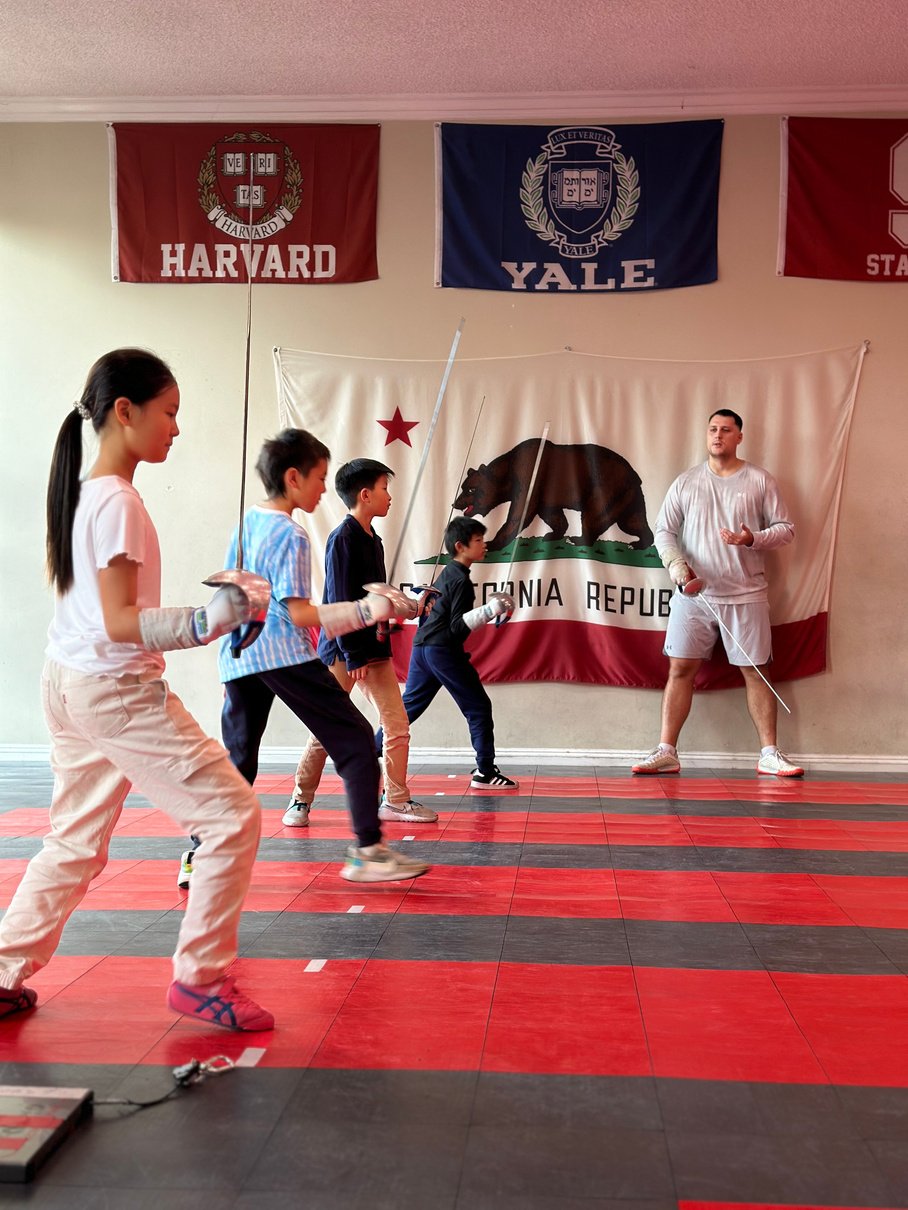 a group of kids practicing fencing in an indoor room