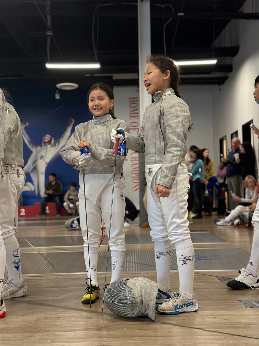 two individuals in fencing gear standing next to each other