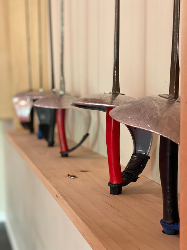  A row of Saber Fencing blades hanging on the wall