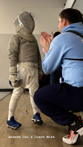 coach Mike coaching a child saber fencer in full fencing fear at a competition 