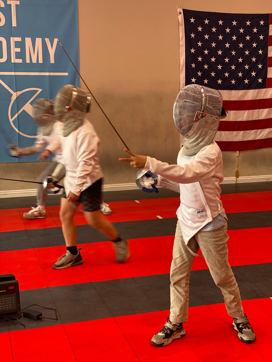 kids in saber fencing class/ birthday party wearing saber mask and holding saber blade. 